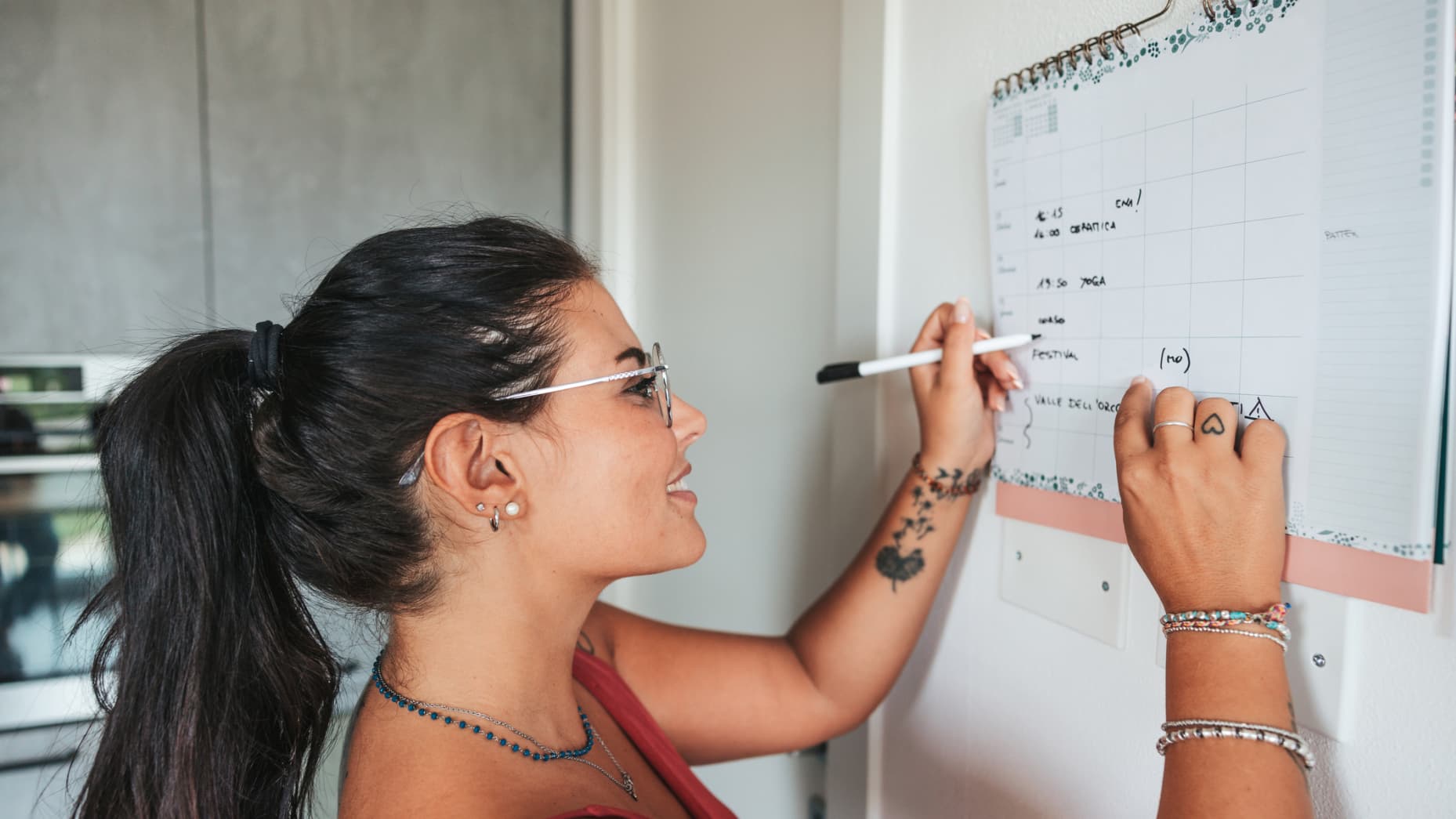 Woman takes note on the kitchen calendar at home.